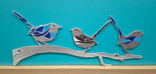 Metal wall art of three birds on a branch against a blue background