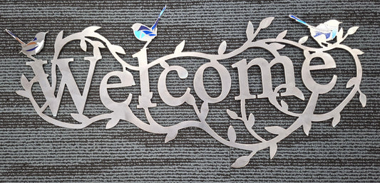 Decorative metal welcome sign with birds on a textured gray background