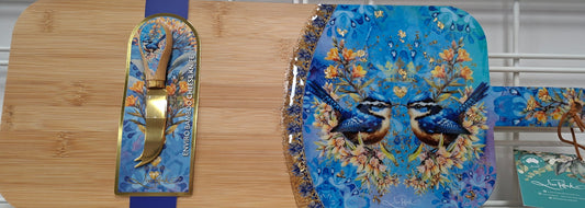Set of decorative cutting boards with floral and bird design on a wooden surface.