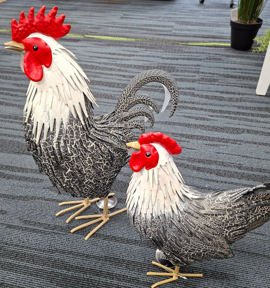 Decorative metal roosters on a textured surface