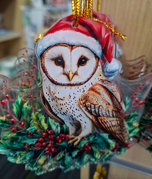 Decorative owl ornament wearing a Santa hat with greenery and berries on a blurred background