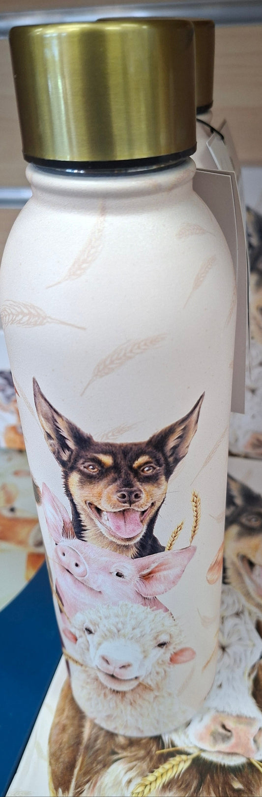 White water bottle with a dog and pig design on a surface with books and a magazine.