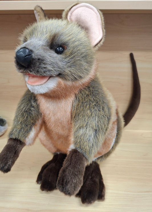 Plush toy resembling a marsupial on a wooden surface